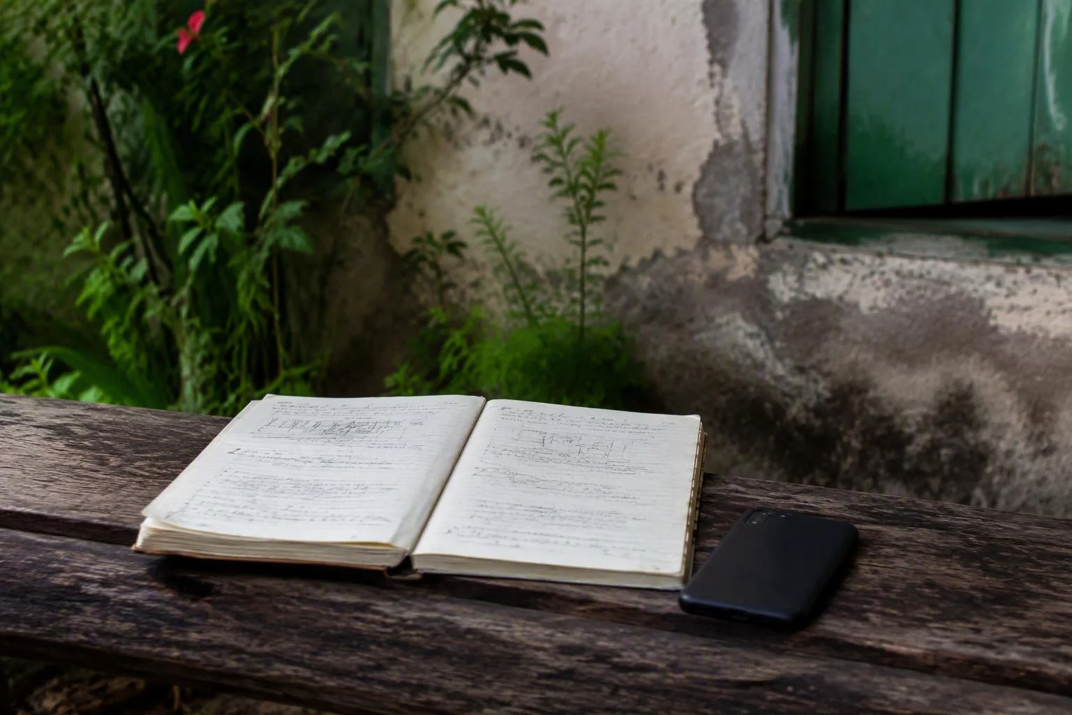 Caderno de campo com anotações de vistoria e um celular ao lado